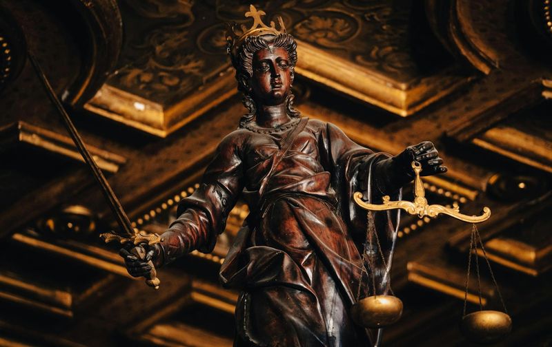 Estátua da Justiça segurando balança e espada em ambiente jurídico, representando o direito à isenção do Imposto de Renda previsto na Lei 7.713/88.
